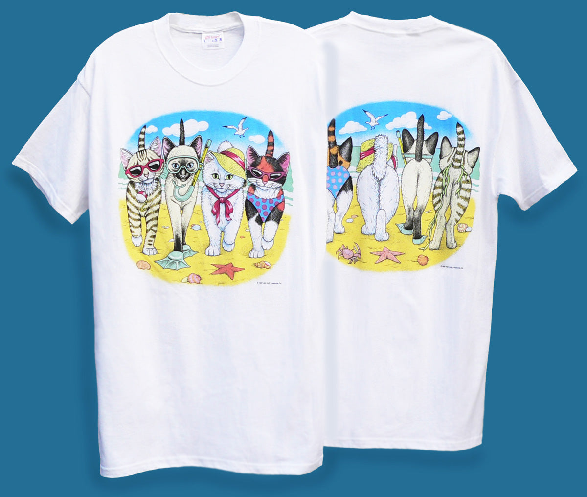 a t-shirts featuring a graphic print of cartoon cats in summer attire on a beach-themed background.