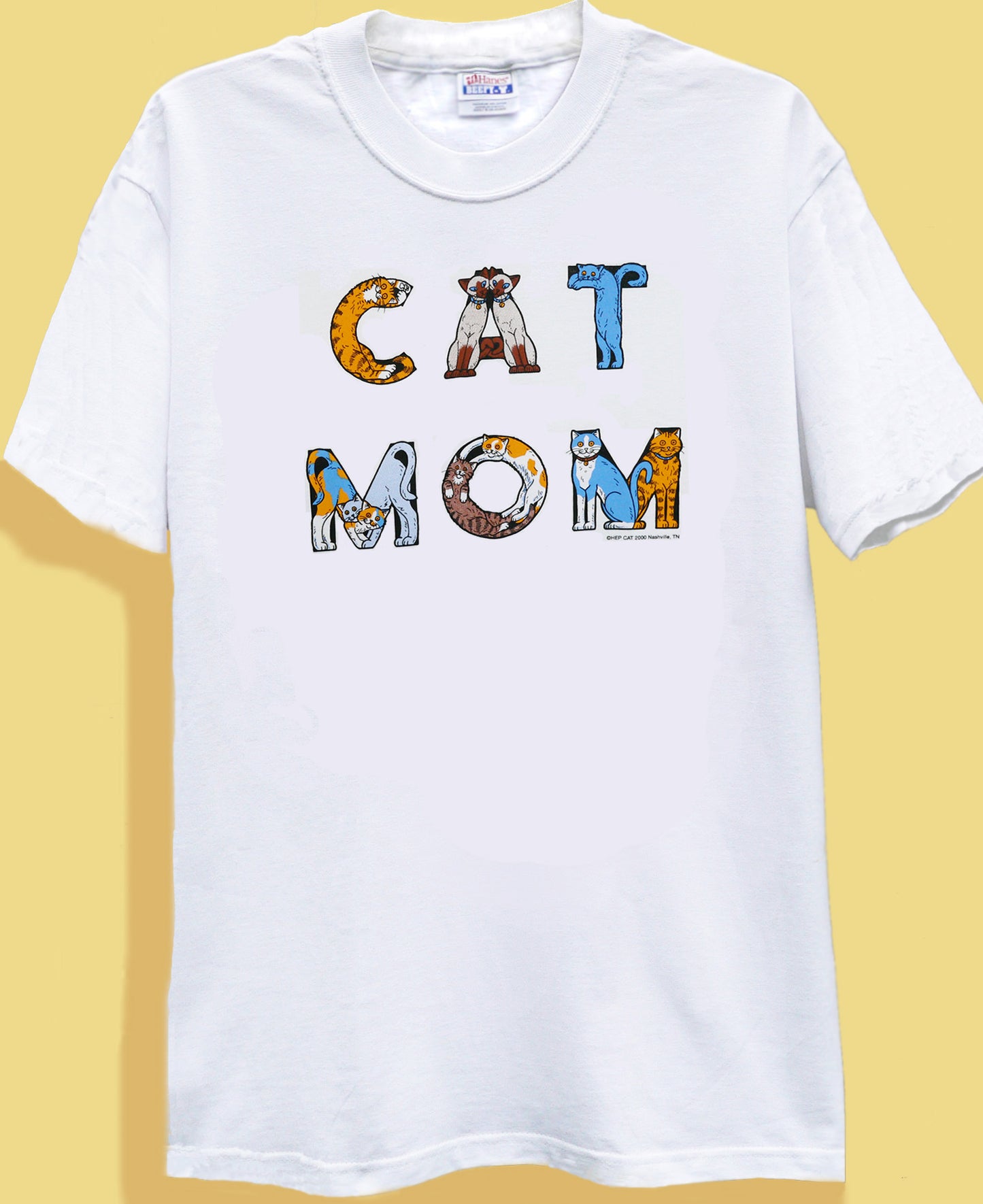 White crew neck t-shirt with the text 'CAT MOM' printed in bold letters, featuring a graphic of a cat in each letter.