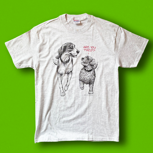 A graphic t-shirt with illustrations of two dogs and the text 'Are You Fixed?' on a green background.