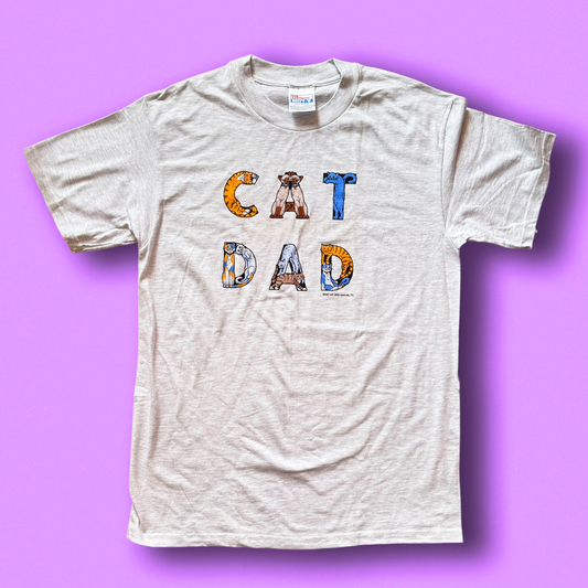 A grey t-shirt with the text 'CAT DAD' printed in bold letters, featuring a graphic of a cat face integrated into the design. Vintage Hep Cat Tee