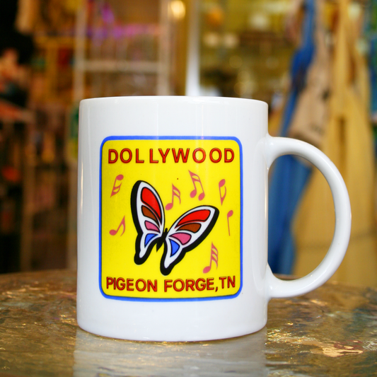 White mug with a yellow graphic featuring a rainbow butterfly and the text "Dollywood, Pigeon Forge, TN"