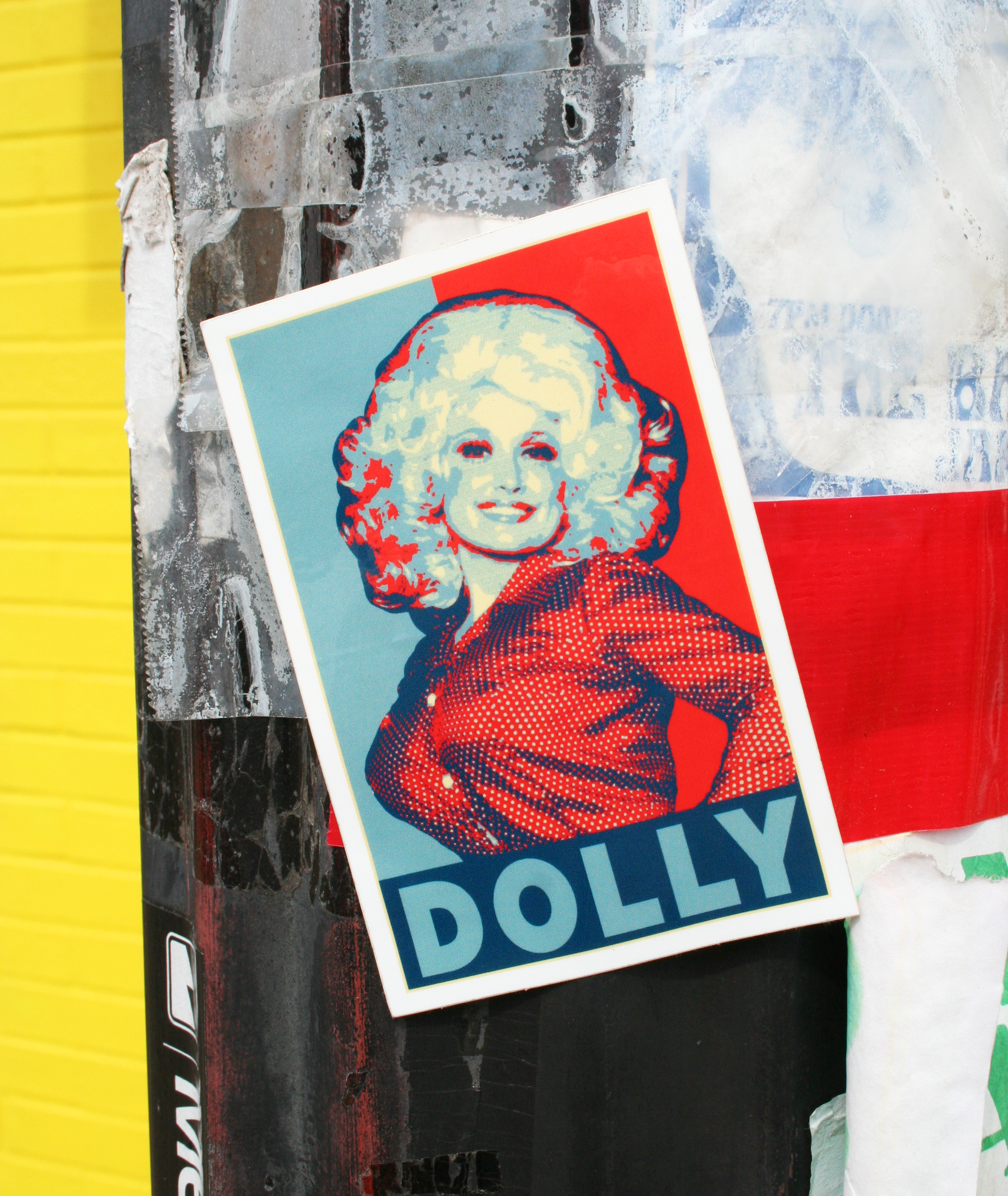 A vinyl sticker with a stylized portrait of Dolly Parton in red, white, and blue tones, with the name 'Dolly' prominently displayed.