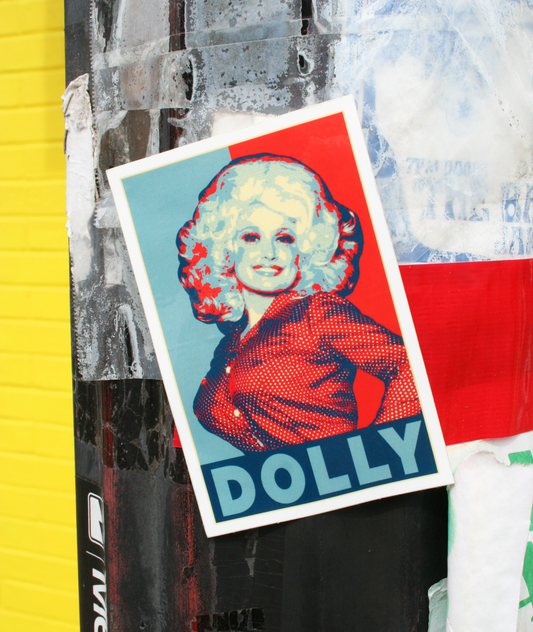 A vinyl sticker with a stylized portrait of Dolly Parton in red, white, and blue tones, with the name 'Dolly' prominently displayed.
