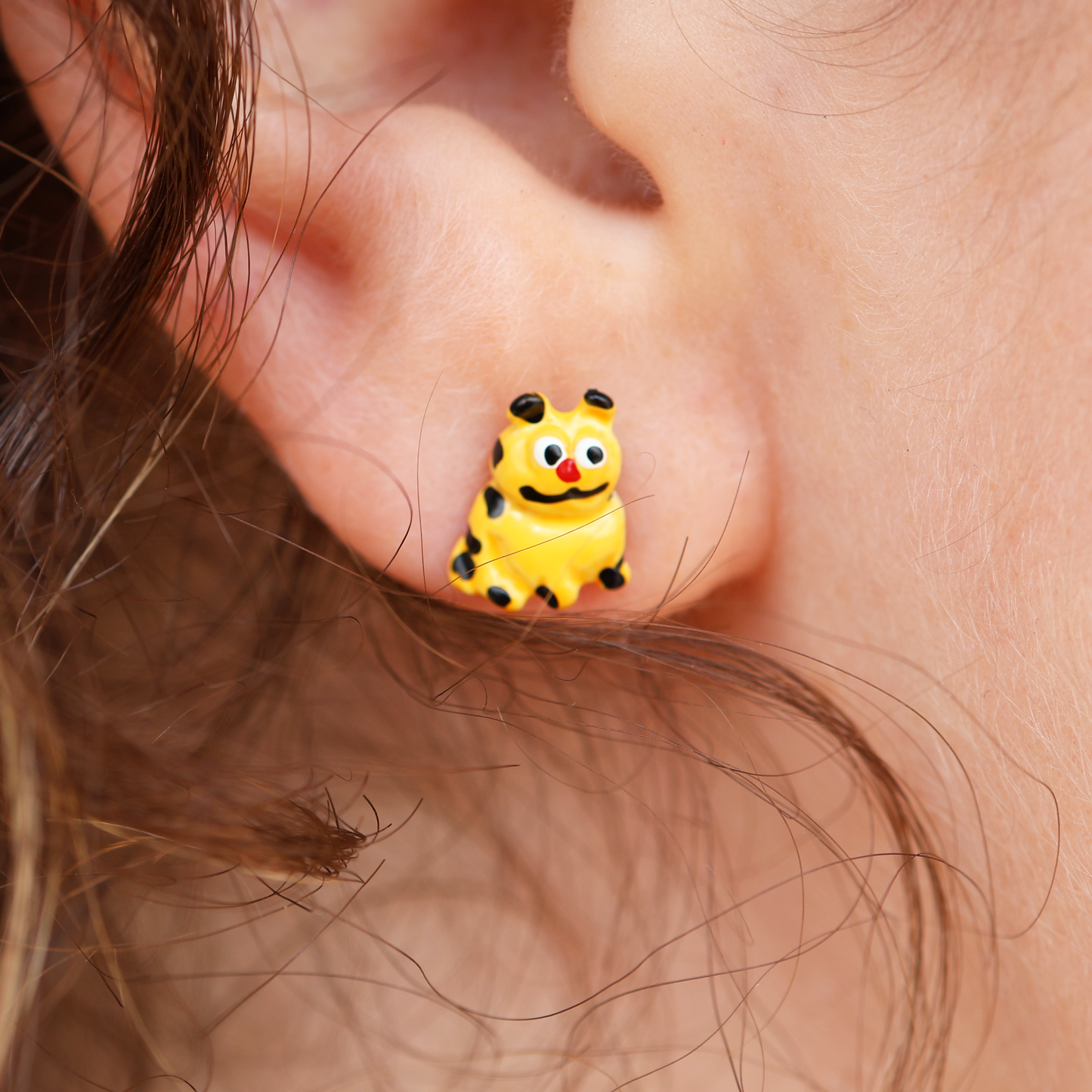 A close-up image of a person wearing a pair of earrings featuring an animated character.