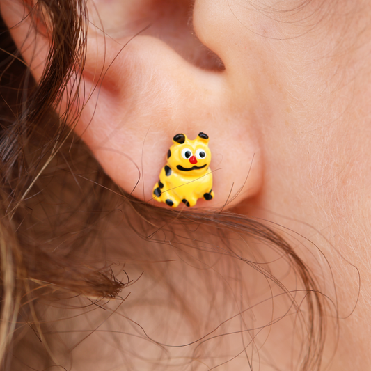 A close-up image of a person wearing a pair of earrings featuring an animated character.