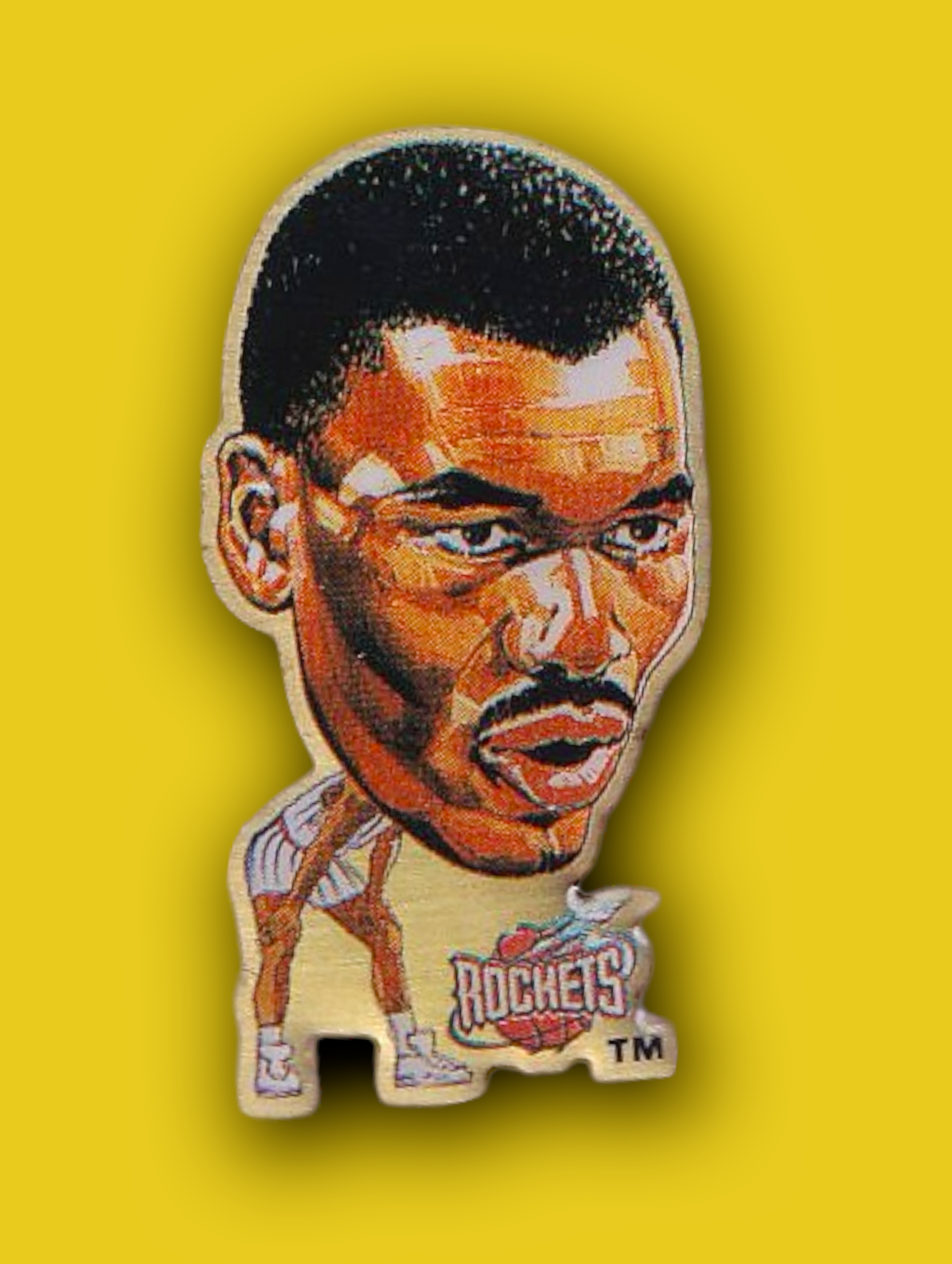 An enamel pin featuring a portrait of Hakeem Olajuwon