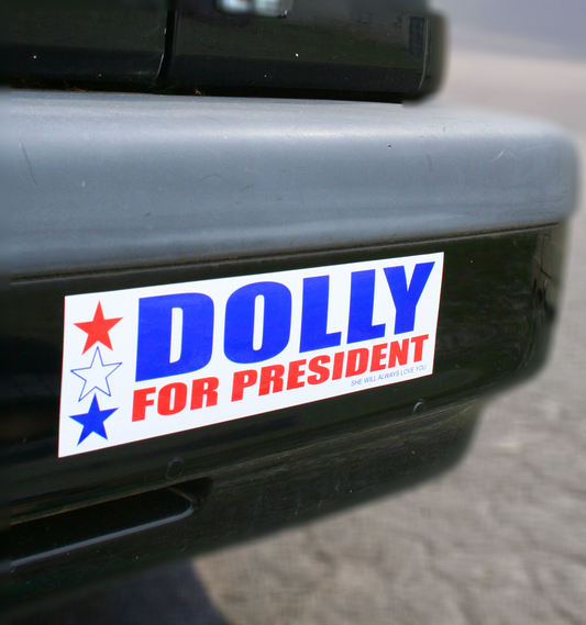 A bumper sticker with the text 'DOLLY FOR PRESIDENT' printed in red and blue colors, featuring a star symbol.