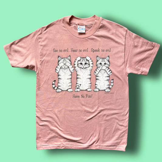 A pink t-shirt with a graphic print of three cats and the text 'See no evil, Hear no evil, Speak no evil, Have No Fun!'