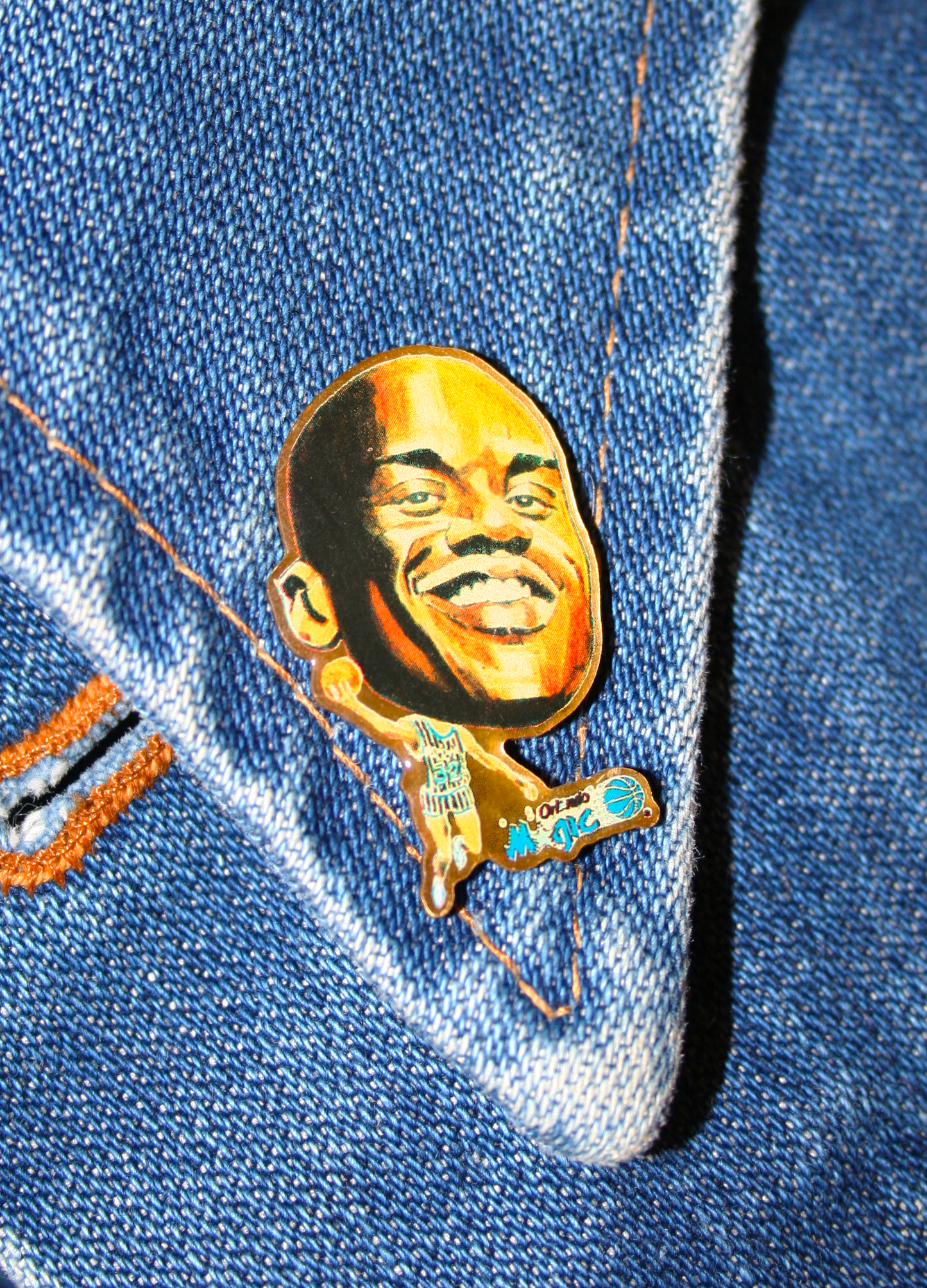 An enamel pin featuring a portrait of a Shaq