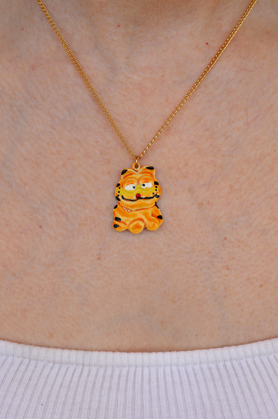 A gold-colored necklace with a character pendant, worn by a person.