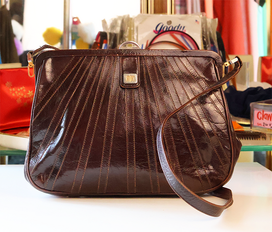 Brown leather handbag on a white surface with a blurred background