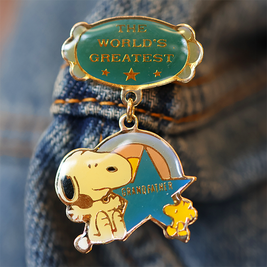 Gold and green enamel pin with 'The World's Greatest Grandfather' text on denim fabric.