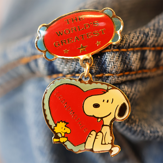Pin with Snoopy holding a heart and 'The World's Greatest' text on denim fabric