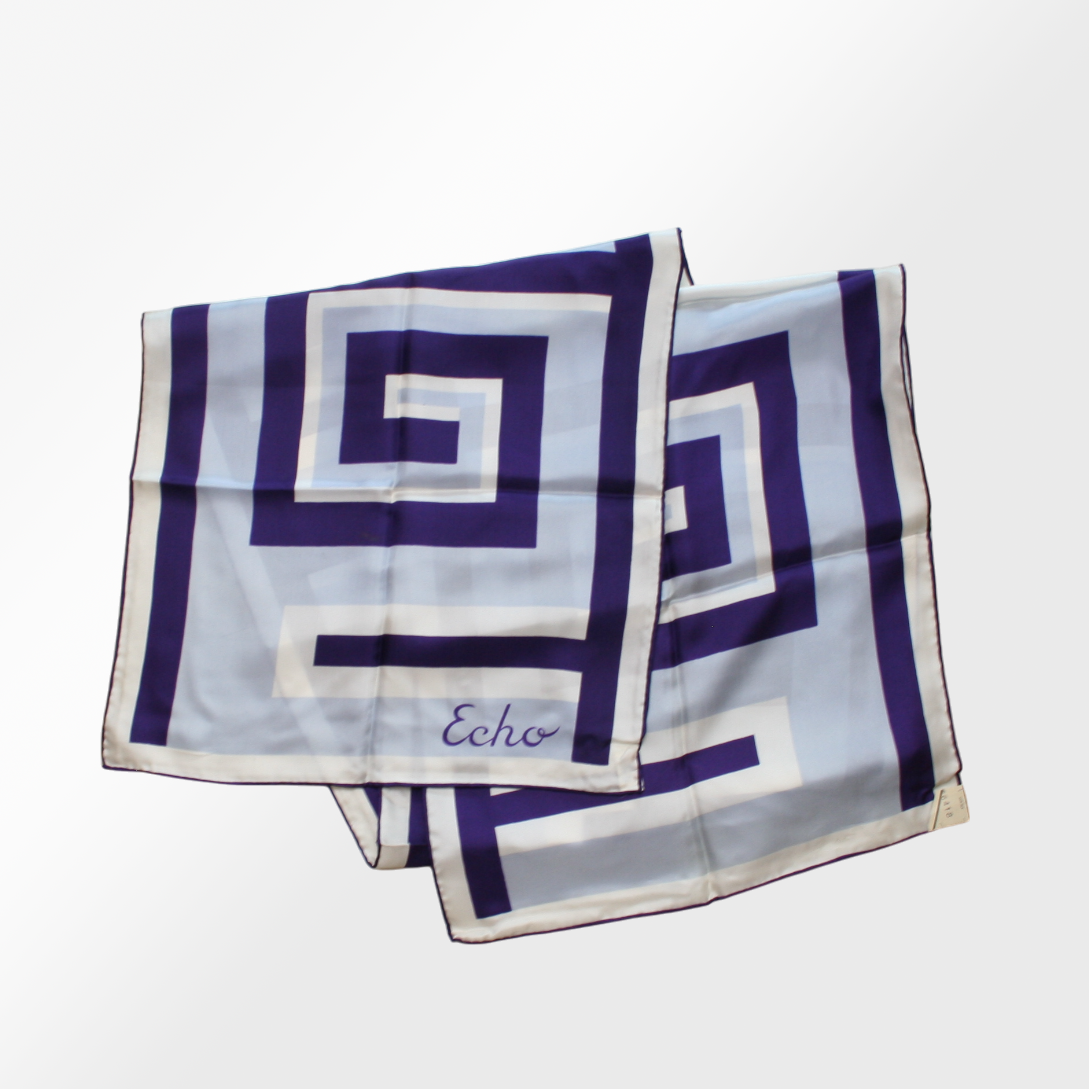 A silk scarf with a Greek key pattern in blue and white, signed with the brand name Echo.