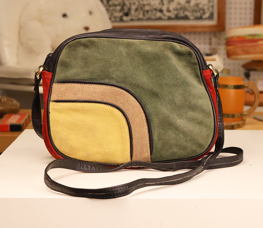 Vintage Niki Milano suede shoulder bag with color blocking in green, yellow, red, and brown, featuring a leather strap and curved panel detailing.