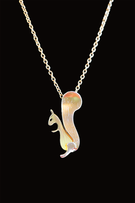 A gold-colored pendant in the shape of a squirrel on a chain against a black background.