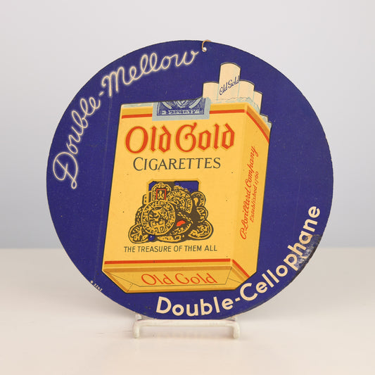 1930s vintage Old Gold Cigarettes packaging on a round blue sign with text.