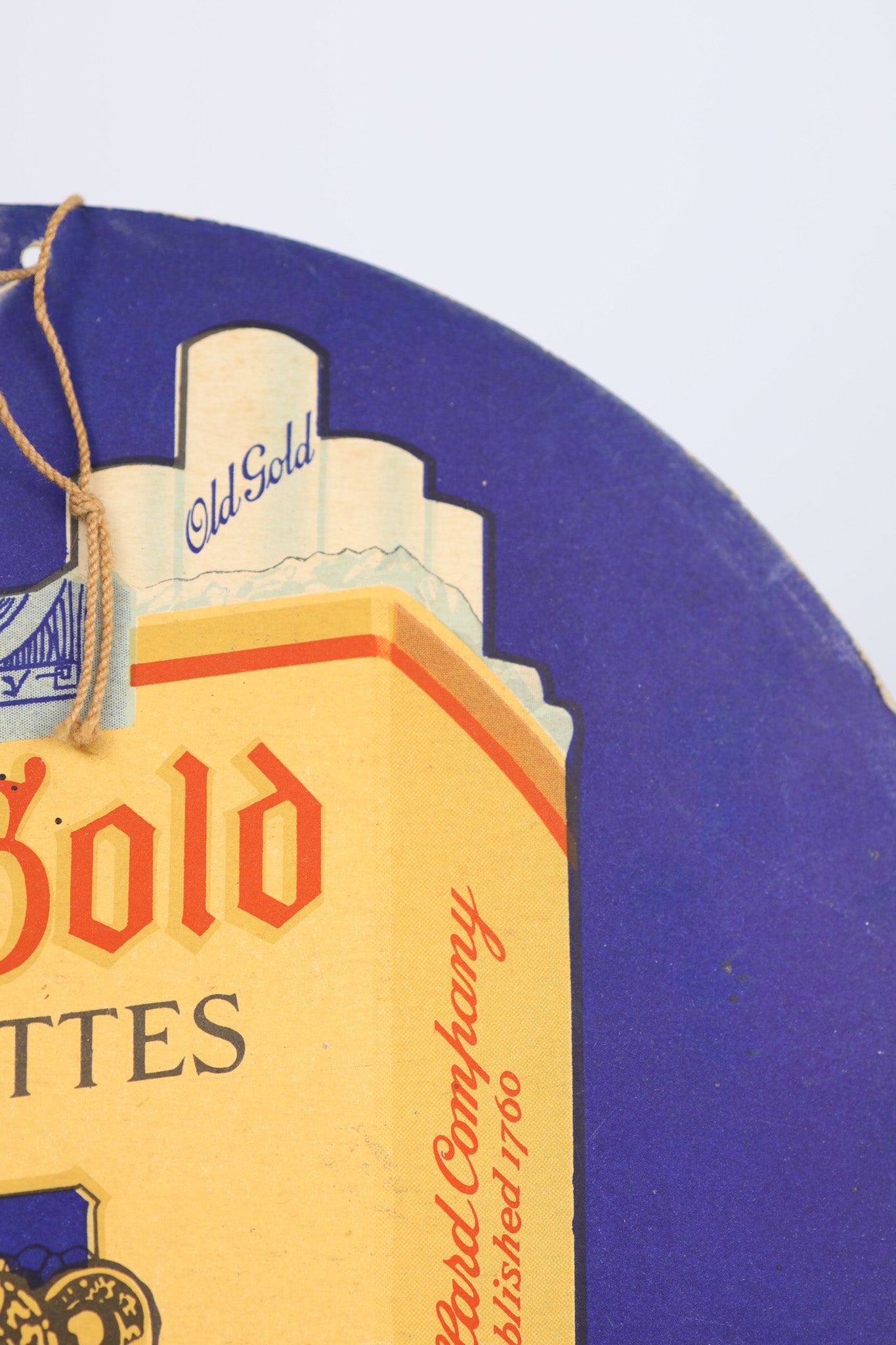 Close-up of a 1930s Old Gold cigarettes sign with a blue background