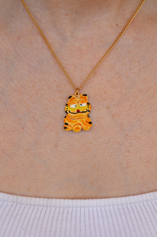 A gold-colored necklace with a character pendant, worn by a person.