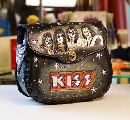 Kiss-themed handbag with band members and logo on a blurred background