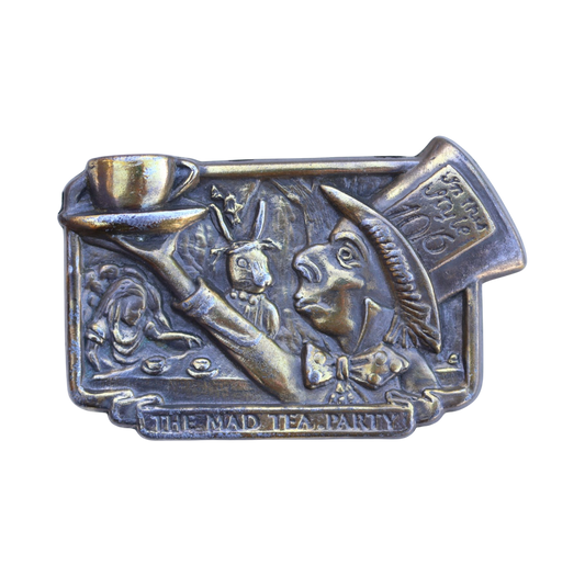 vintage brass belt buckle featuring the tea party scene from alice in wonderland with the mad hatter, alice, and the white rabbit