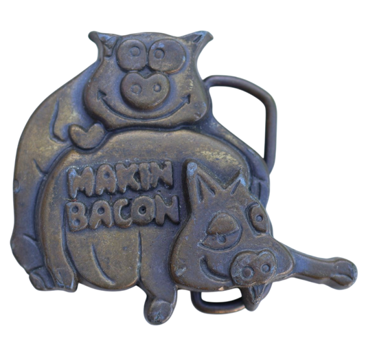 vintage belt buckle featuring two pigs in a suggestive position
