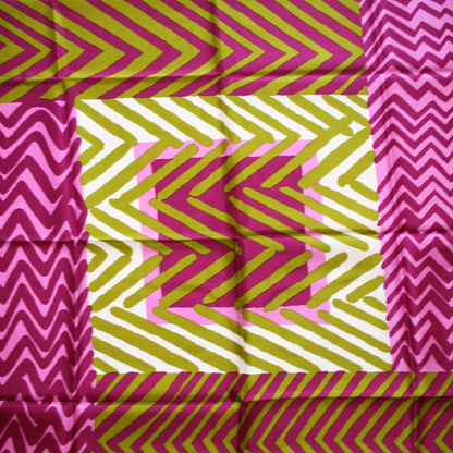 A close-up of a silk scarf with a geometric pattern in vibrant colors, featuring pink, green, and yellow stripes on a white background.