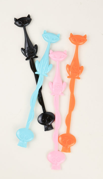 Set of colorful cat-shaped stir sticks on a white background by Shag Josh Agle