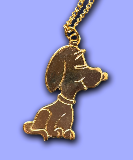 A vintage gold-tone pendant featuring the character Snoopy from Peanuts in profile view.