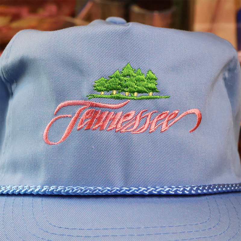 Blue cap with embroidered 'Tennessee' and landscape design on a blurred background