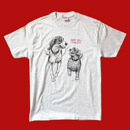 A graphic t-shirt with illustrations of two dogs and the text 'Are You Fixed?' on a green background.