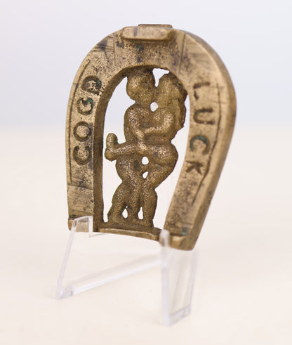 Decorative horseshoe with a naughty figure and 'Good Luck' text on a white background