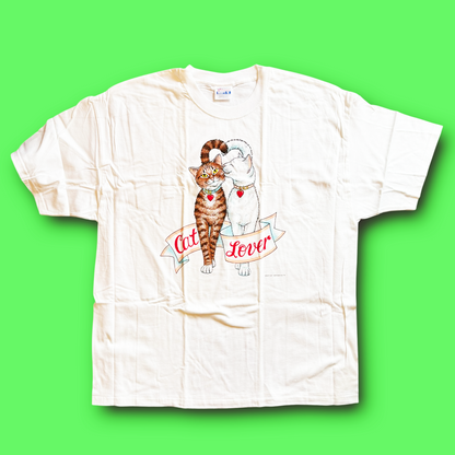 A white vintage t-shirt with a graphic of a cat and the text 'Cat Lover' on it, displayed against a green background.