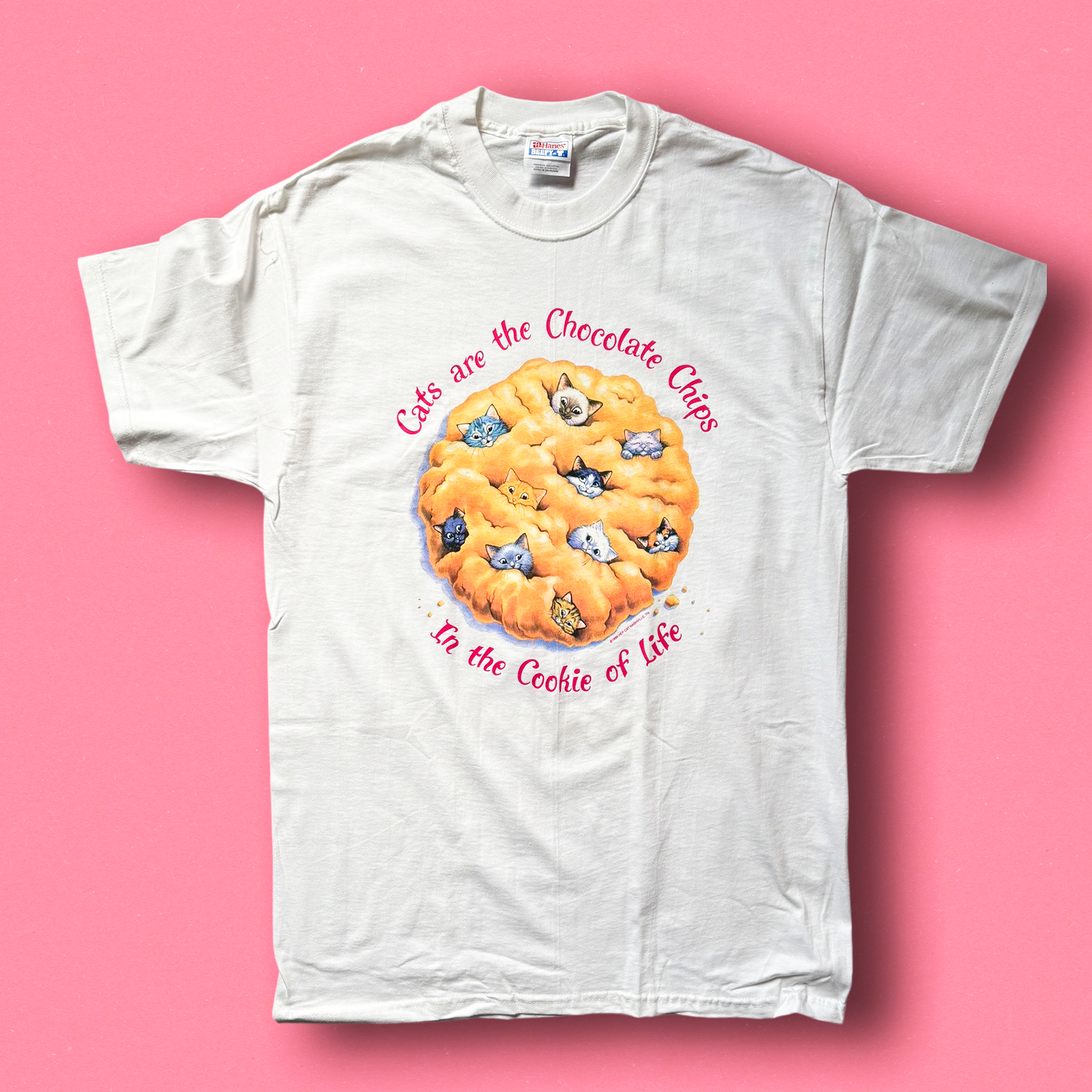 White crew neck t-shirt with a graphic of a chocolate chip cookie and text 'Cats are the Chocolate Chips to the Cookie of Life'.