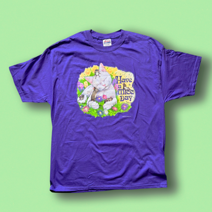 A purple crew neck t-shirt with a graphic print in the center, featuring a cat and the text 'Have a Mice Day' on a green background.