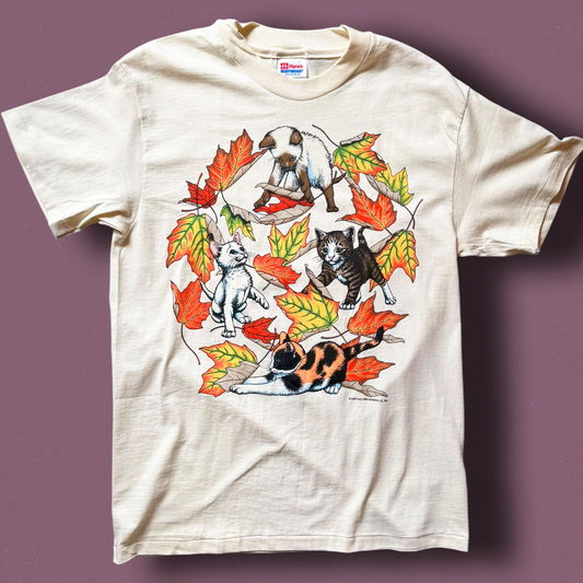 A vintage cat-themed t-shirt with graphic prints of cats and autumn leaves on a light background.