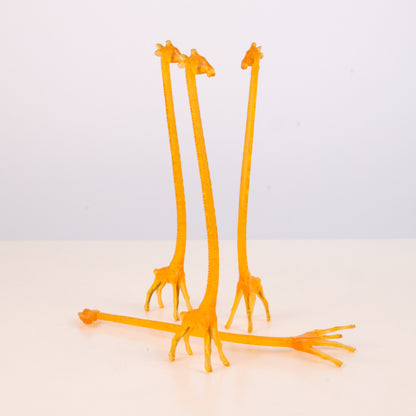 Four Vintage 1960s  orange giraffe-shaped stir sticks on a light gray background