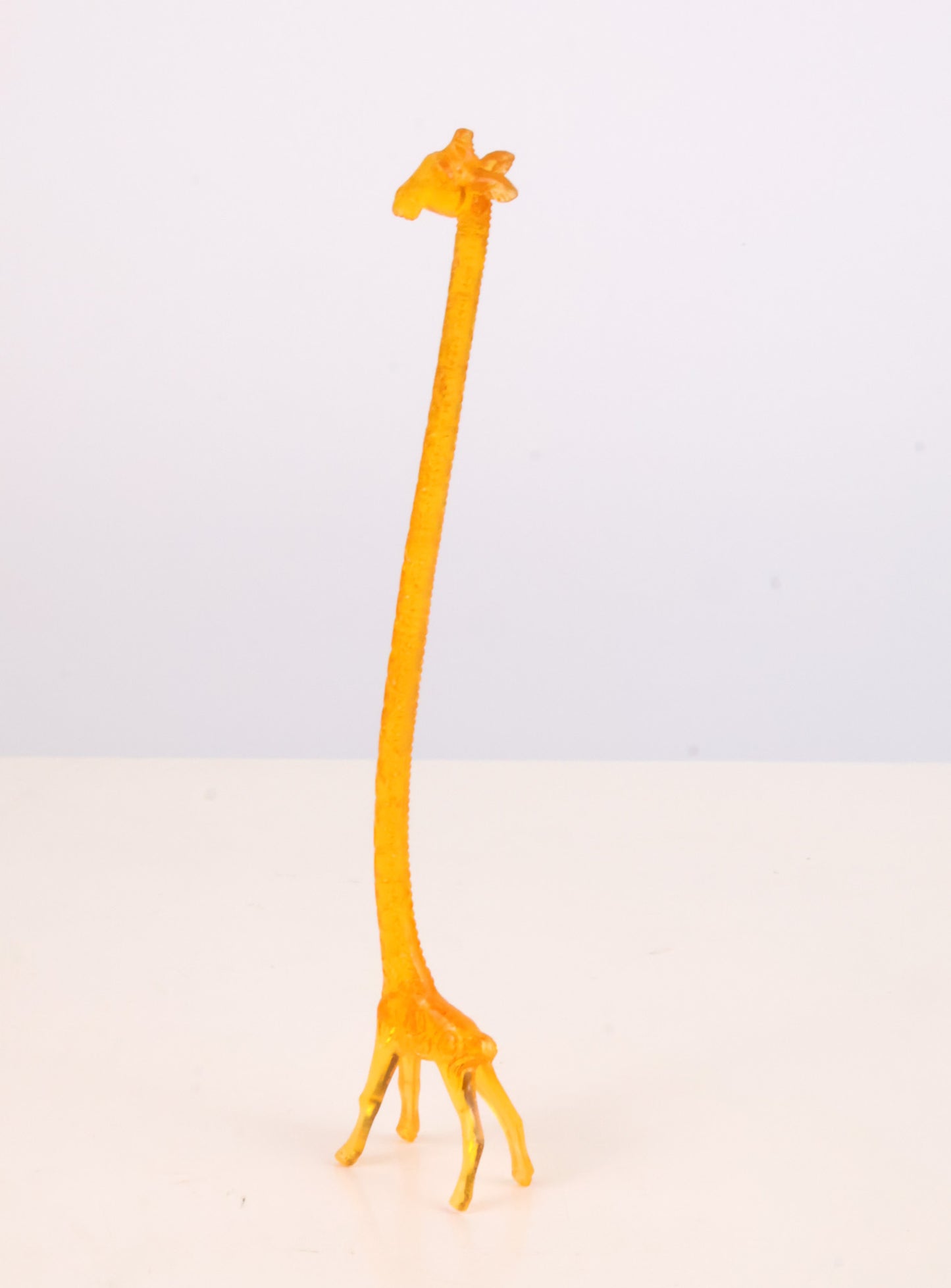 Yellow giraffe swizzle stick on a light gray background