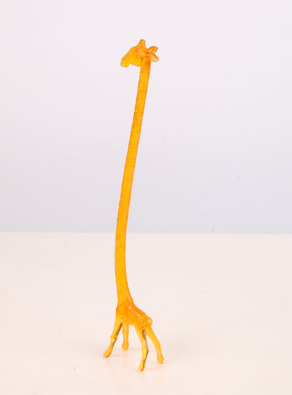Yellow giraffe swizzle stick on a light gray background