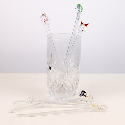 Set of glass swizzle sticks with animal ends in a clear glass on a white background