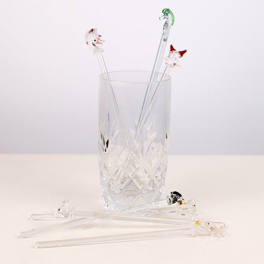 Set of glass swizzle sticks with animal ends in a clear glass on a white background