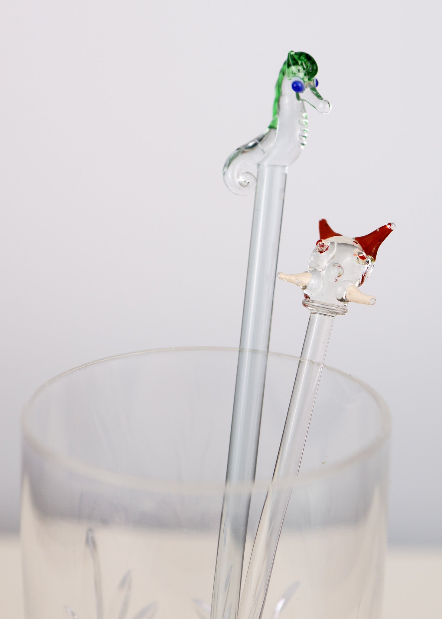 Decorative glass swizzle sticks with a seahorse design on a white background
