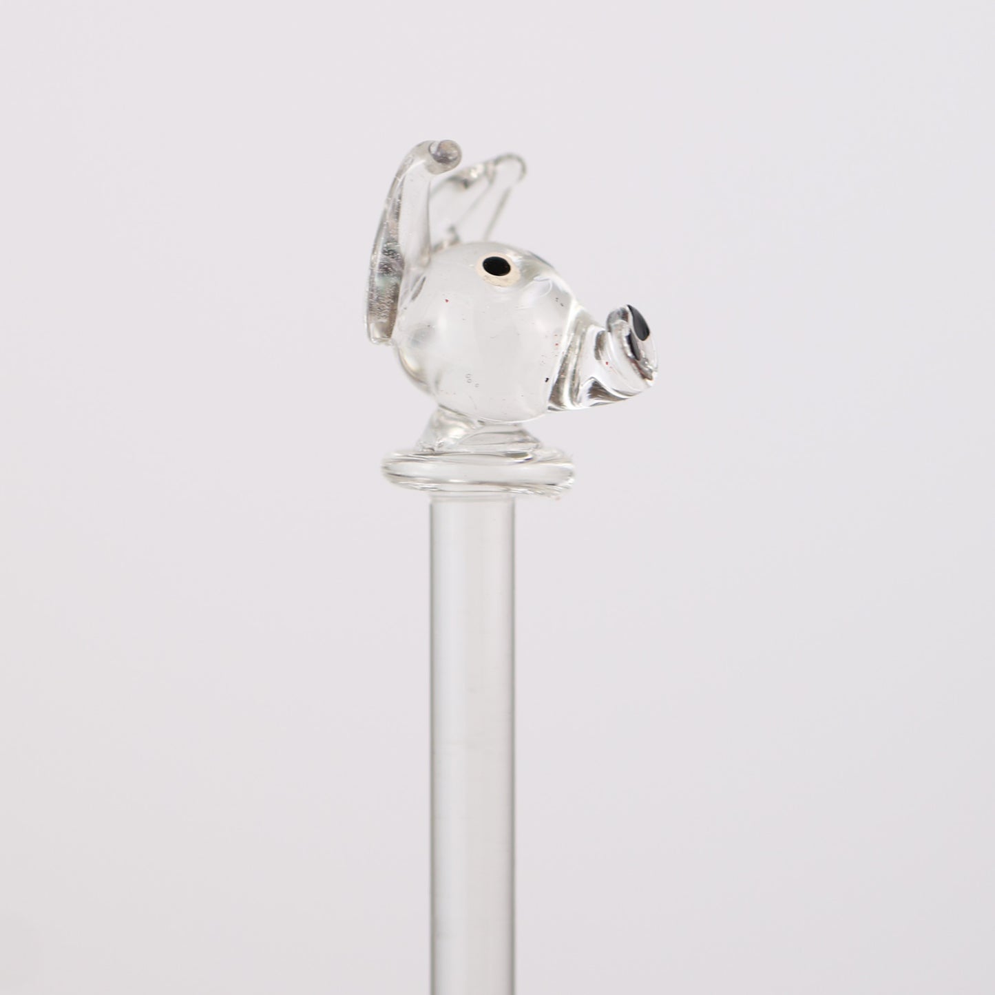Clear glass swizzle stick with a dog design on a white background
