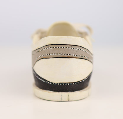 White sneaker with black sole on a light gray background