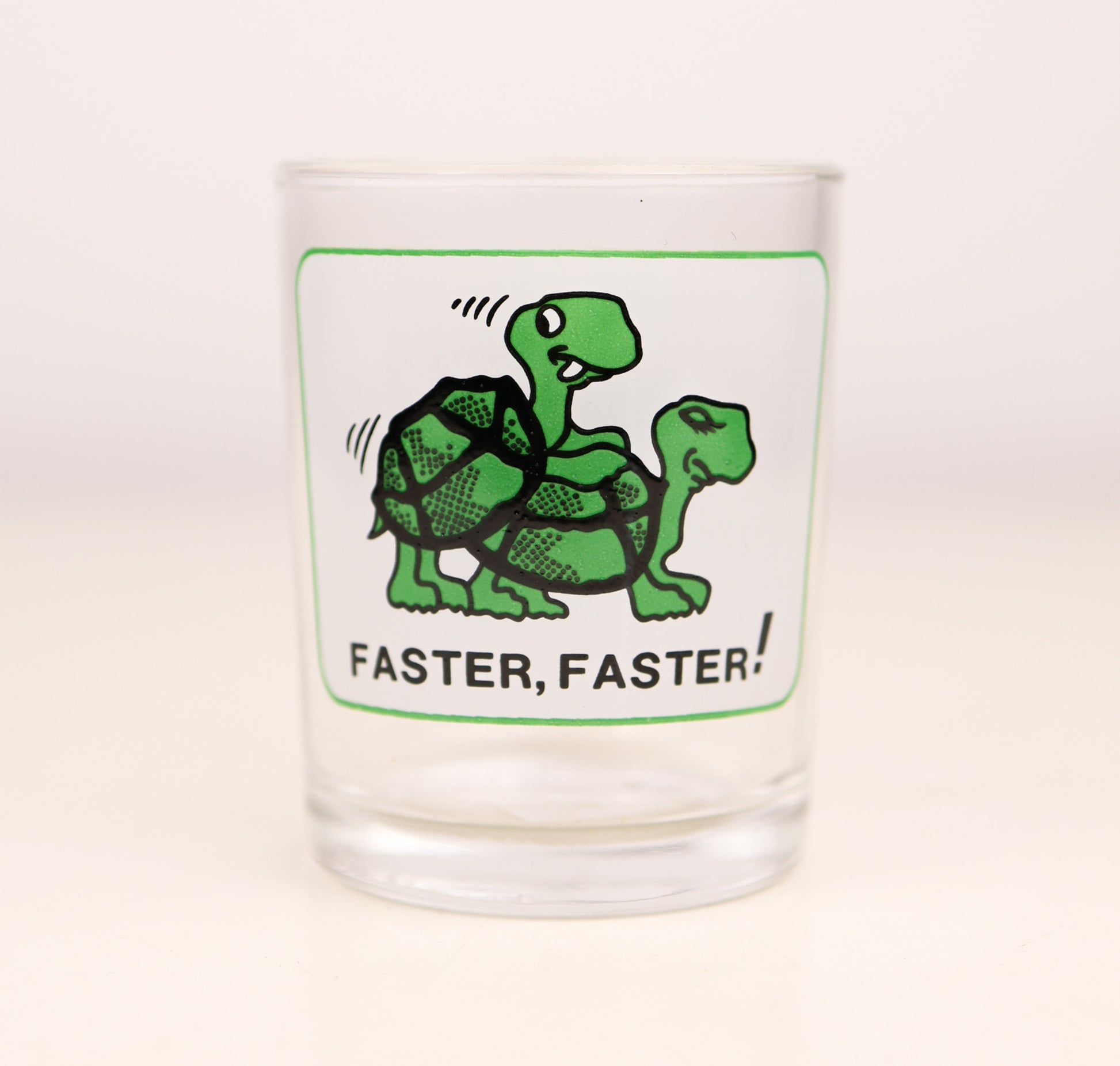 Vintage Clear shot glass with naughty green turtle illustration and 'Faster, Faster!' text on a white background